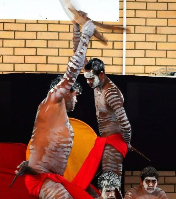 Dancers in white body paint mid-performance with a boomerang